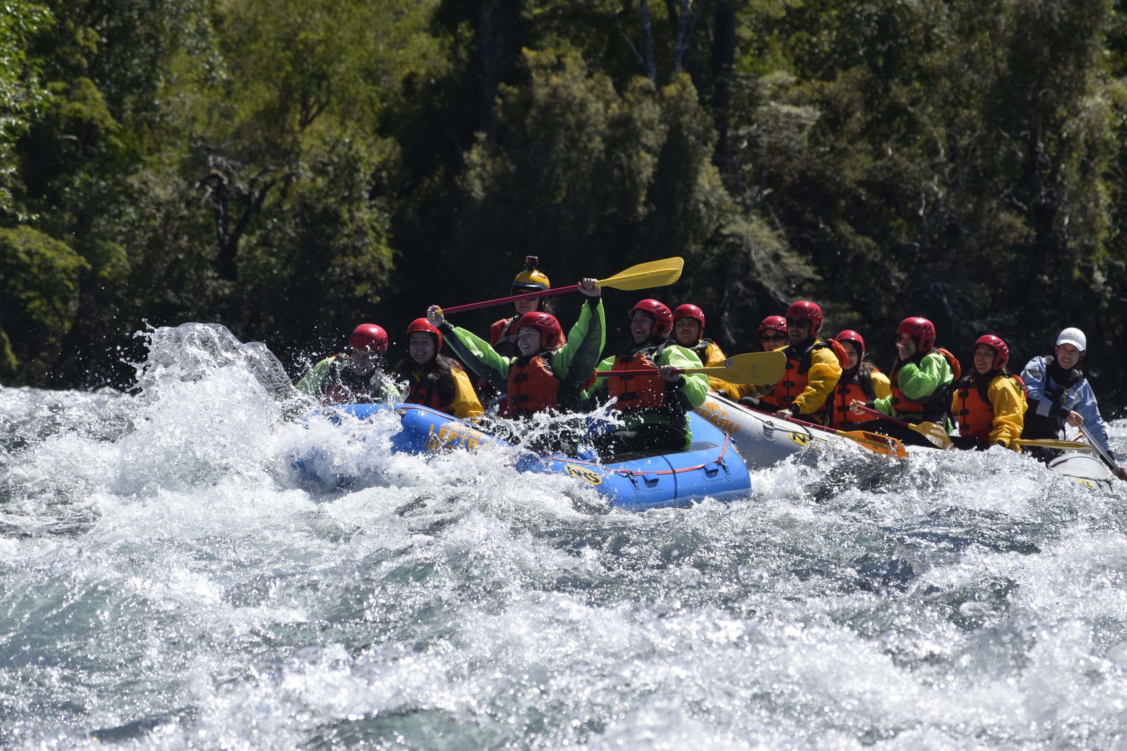 Grupo de estudiantes haciendo rafting con cascadas y equipo de seguridad